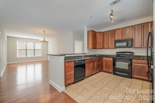 a kitchen with stainless steel appliances granite countertop a stove top oven a sink dishwasher and a refrigerator with wooden floor
