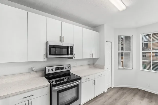 a kitchen with granite countertop a stove a sink and a white cabinets