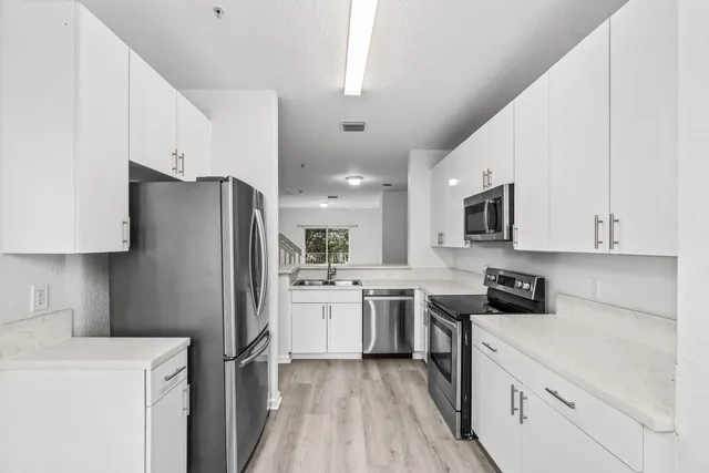 a kitchen with stainless steel appliances a refrigerator sink and white cabinets