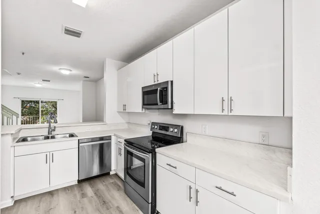 a kitchen with a sink white cabinets and white appliances