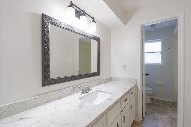 a bathroom with a granite countertop sink mirror and a toilet