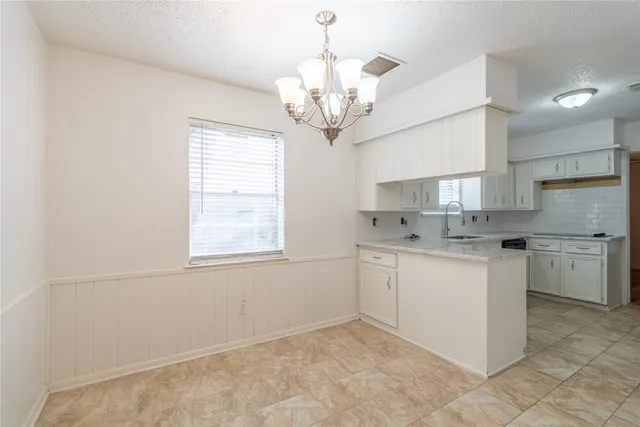 a kitchen with a white cabinets and chandelier