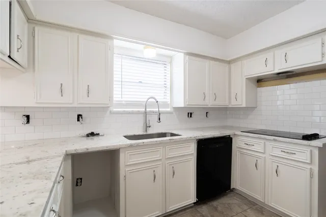 a kitchen with white cabinets appliances a sink and a window