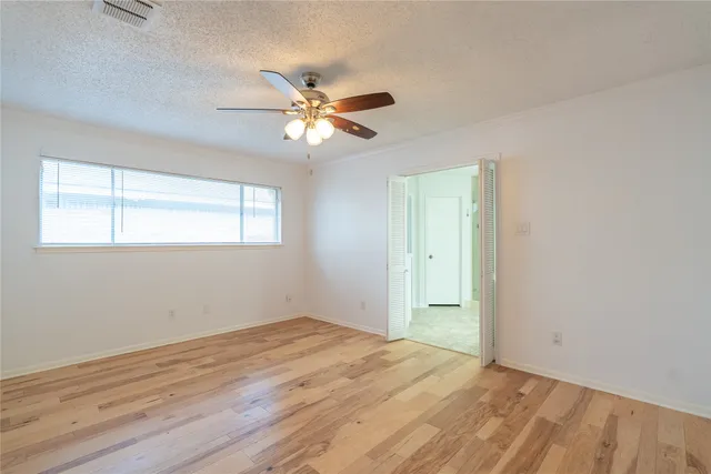 a view of empty room with wooden floor and fan