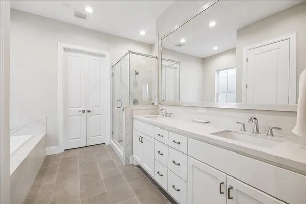 a bathroom with a sink double vanity granite tub shower and mirror