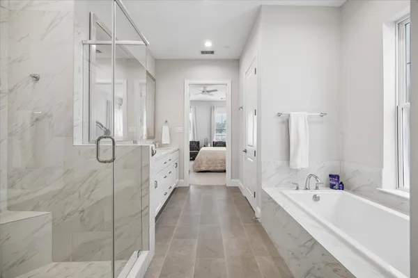a spacious bathroom with a tub shower and mirror