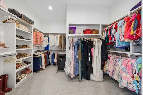 a view of walk in closet with clothes and shoes