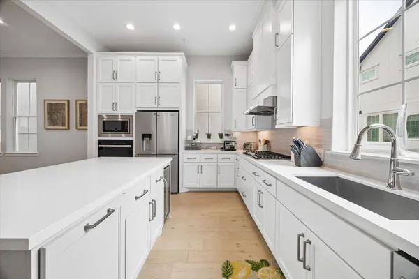 a kitchen that has a lot of white cabinets and stainless steel appliances