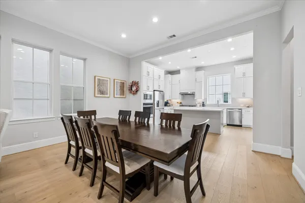a kitchen with a dining table chairs and wooden floor