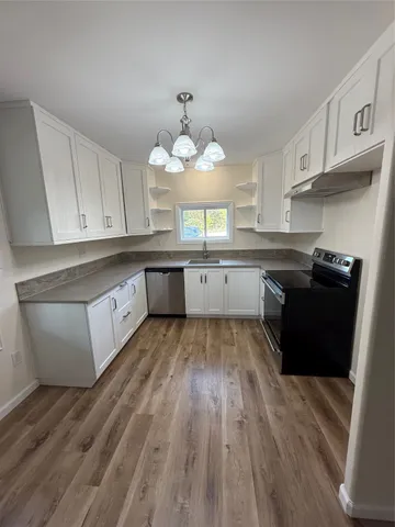 a large kitchen with wooden floors and stainless steel appliances