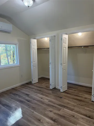 an empty room with wooden floor closet and windows