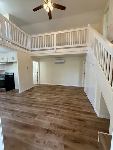 a view of an empty room with chandelier fan and wooden floor
