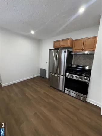 a kitchen with granite countertop a refrigerator and a stove top oven