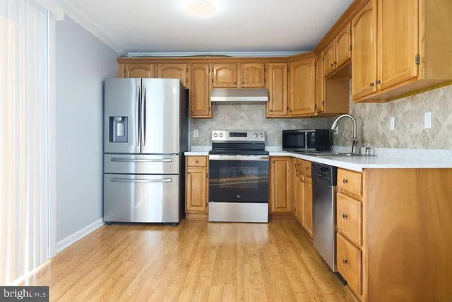 a kitchen with stainless steel appliances granite countertop a refrigerator sink and wooden cabinets