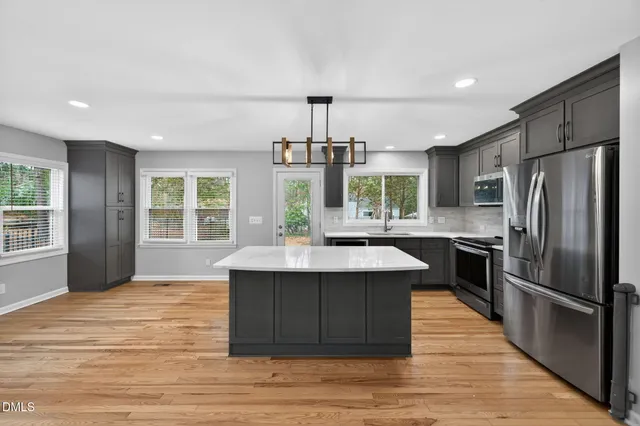 a kitchen with kitchen island granite countertop a sink appliances and cabinets