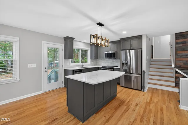 a kitchen with stainless steel appliances granite countertop a sink dishwasher a refrigerator and a stove with wooden floor