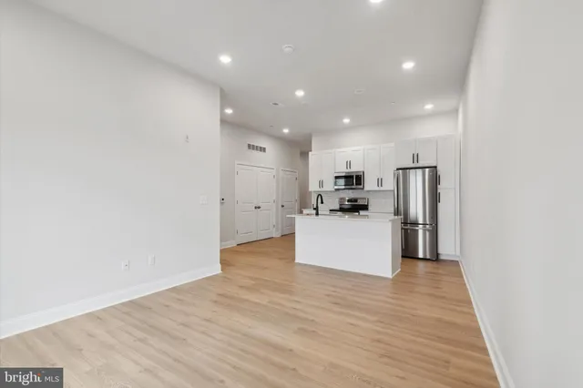 a view of kitchen with kitchen island a sink wooden floor and a refrigerator