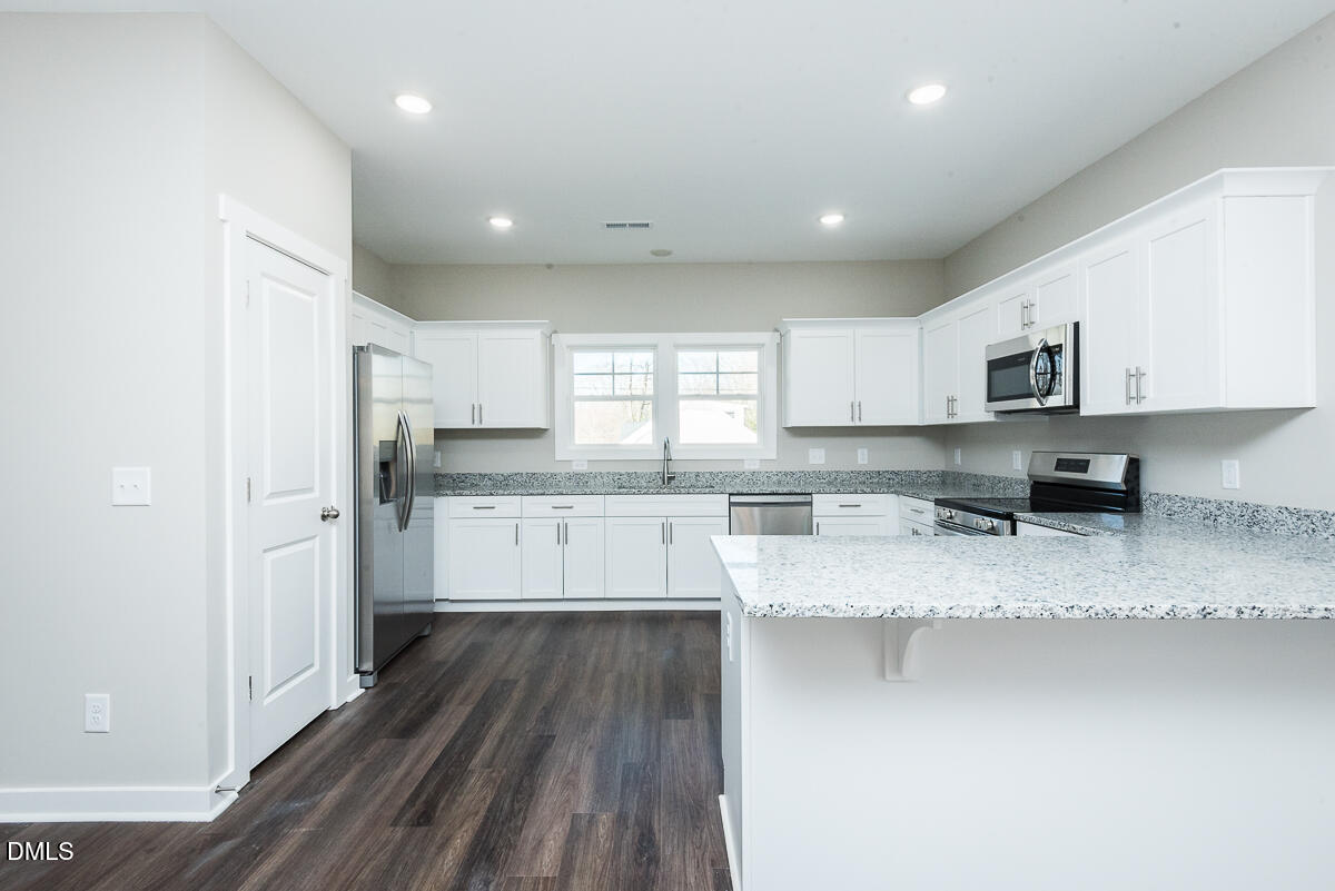 2828 Ricolden Trail Elon, NC 27244 - Photo 12 of 14 a kitchen with stainless steel appliances granite countertop a refrigerator sink and cabinets