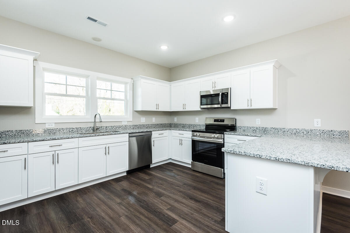 2828 Ricolden Trail Elon, NC 27244 - Photo 2 of 14 a kitchen with granite countertop white cabinets and a wooden floor