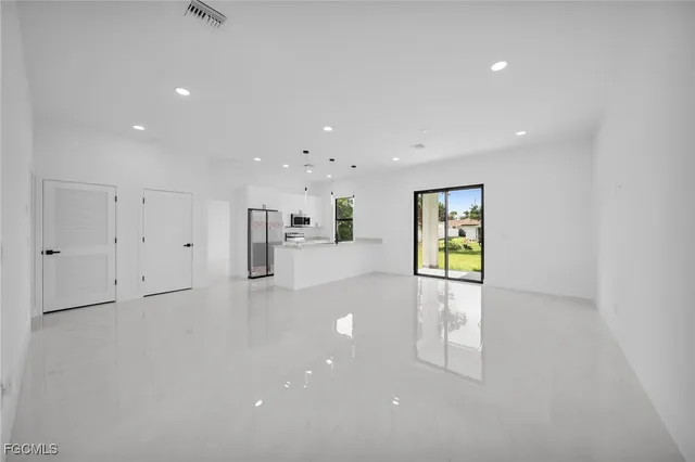 a view of an empty room with window and wooden floor