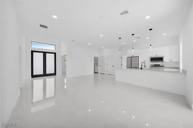 a view of kitchen with refrigerator and white cabinets