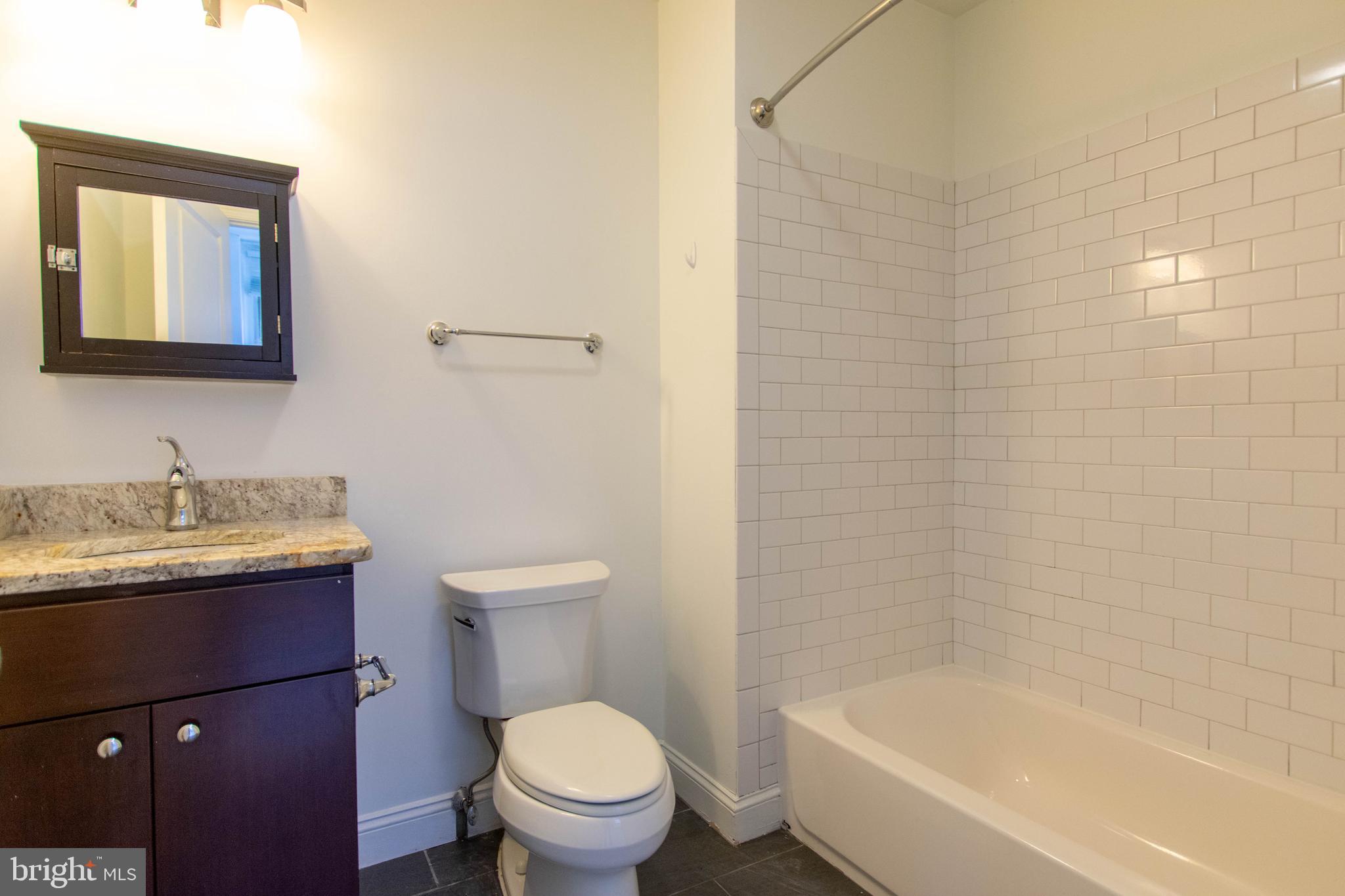427-33 Monroe Street, Unit 102 Philadelphia, PA 19147 - Photo 16 of 23 a bathroom with a granite countertop toilet a sink and a bathtub