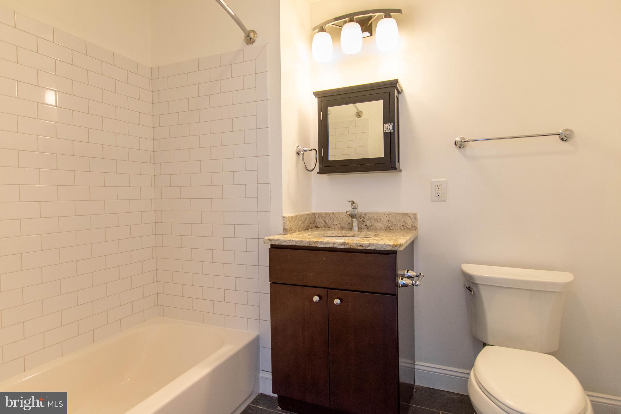 427-33 Monroe Street, Unit 102 Philadelphia, PA 19147 - Photo 21 of 23 a bathroom with a granite countertop toilet sink and mirror