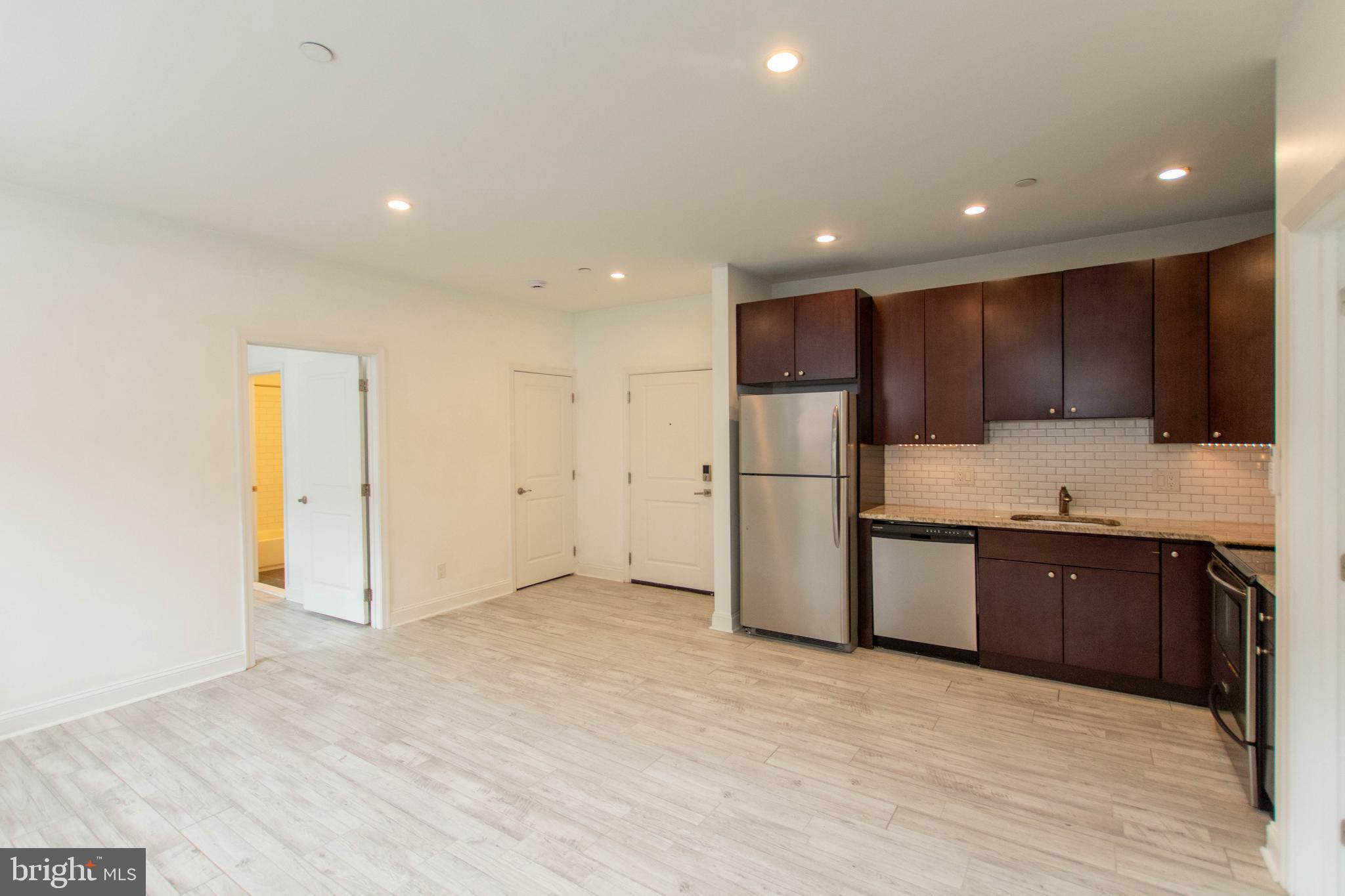 427-33 Monroe Street, Unit 102 Philadelphia, PA 19147 - Photo 5 of 23 a large kitchen with stainless steel appliances granite countertop a refrigerator and a sink
