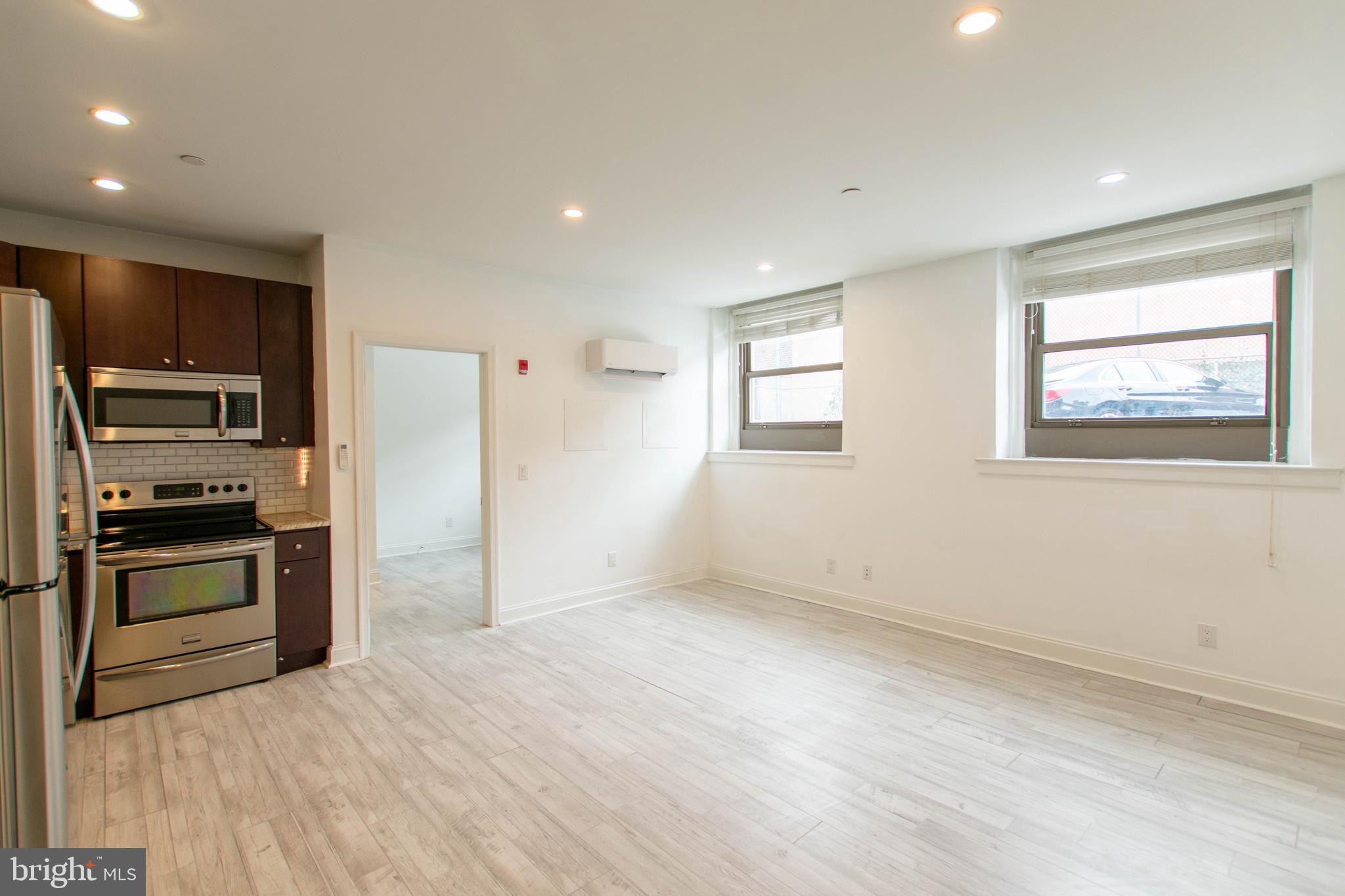 427-33 Monroe Street, Unit 102 Philadelphia, PA 19147 - Photo 8 of 23 a view of a kitchen with wooden floor electronic appliances and windows