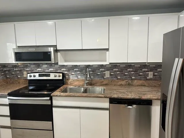 a kitchen with stainless steel appliances granite countertop a stove a refrigerator and a sink