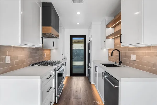 a kitchen with sink a stove and white cabinets