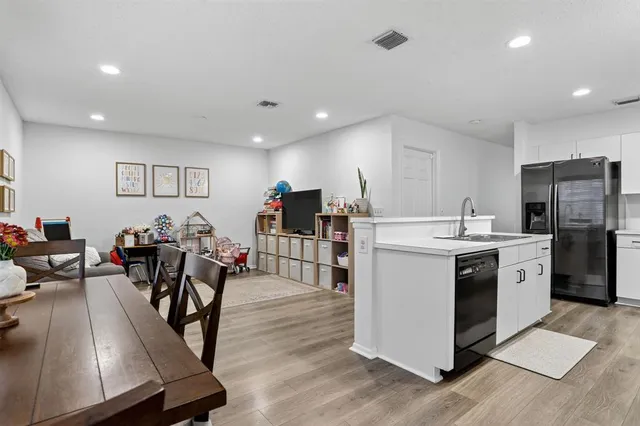 a kitchen with stainless steel appliances kitchen island granite countertop a stove a refrigerator a dining table and chairs with wooden floor