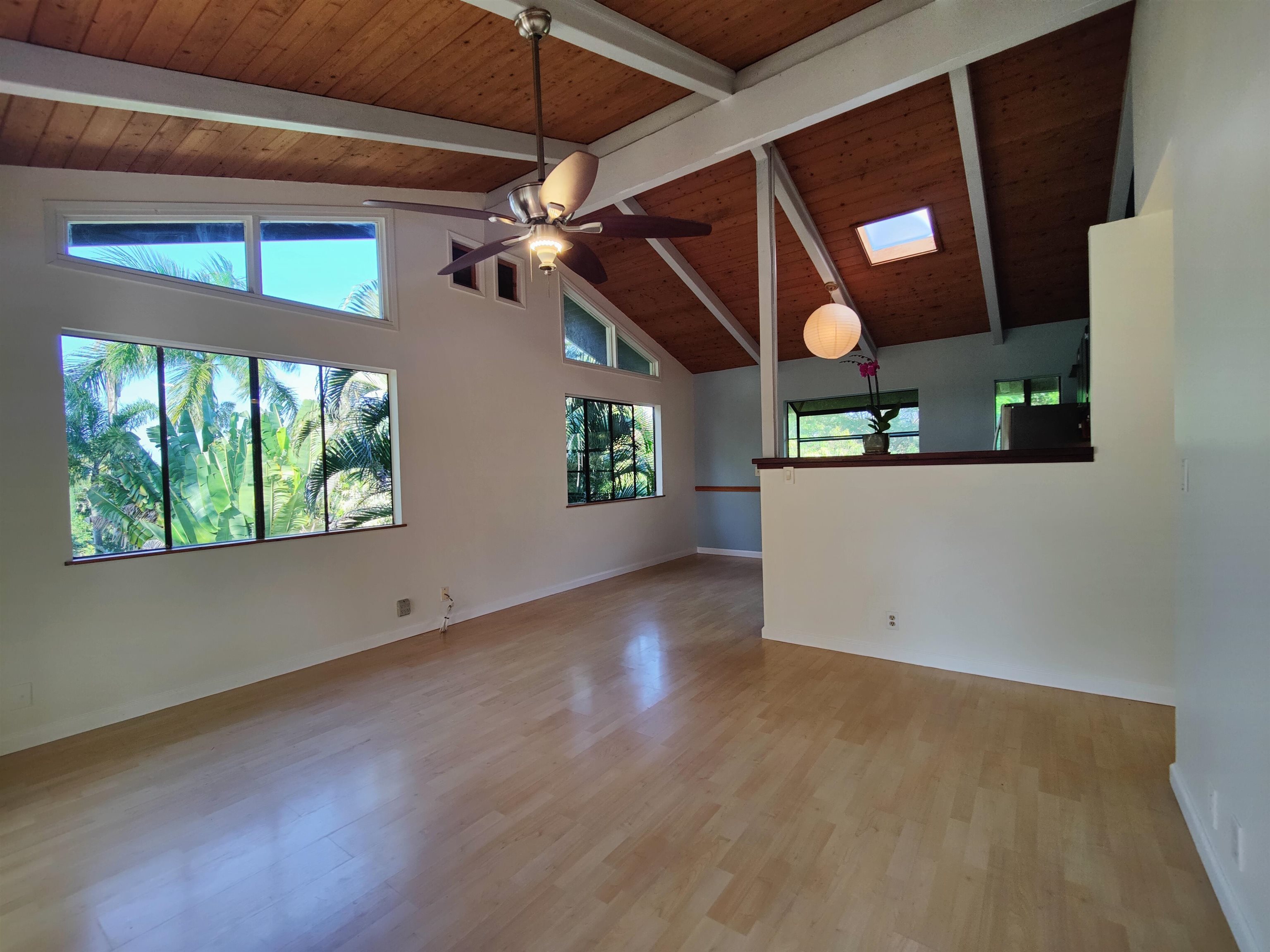 142 Peahi Road Haiku, HI 96708 - Photo 2 of 21 an empty room with wooden floor fan and windows