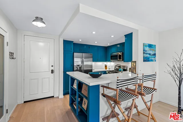 a open kitchen with stainless steel appliances granite countertop a stove top oven a dining table and chairs with wooden floor