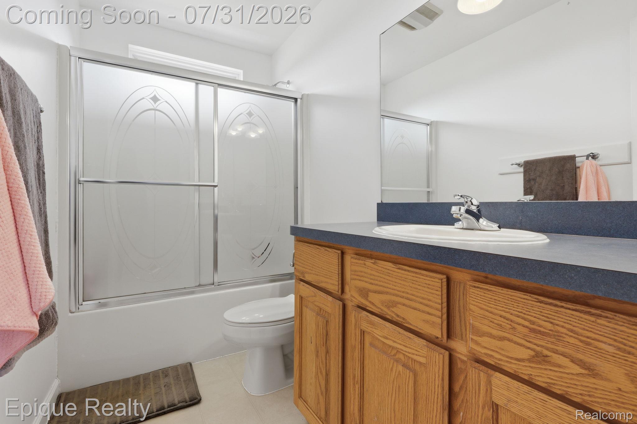 10179 Duffield Road Gaines, MI 48436 - Photo 15 of 30 Bathroom featuring a light wood-finish vanity with a built-in sink, a dark countertop, and an expansive wall mirror