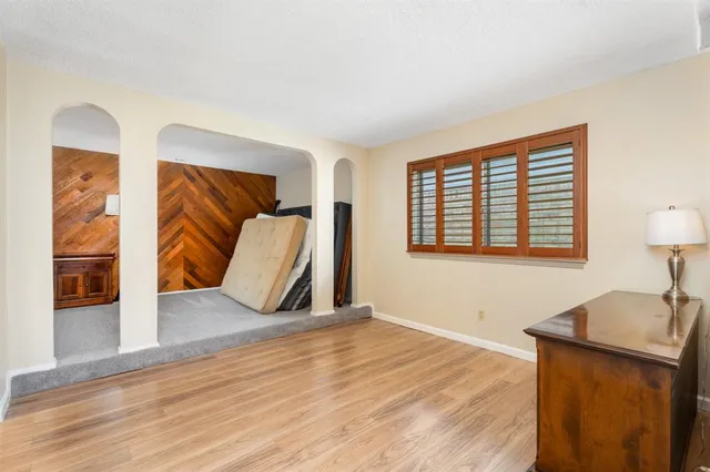 a view of an empty room with wooden floor and a window
