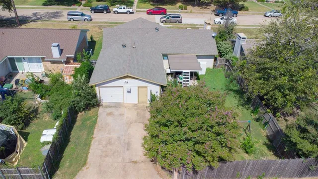 an aerial view of a house with a yard and a large tree