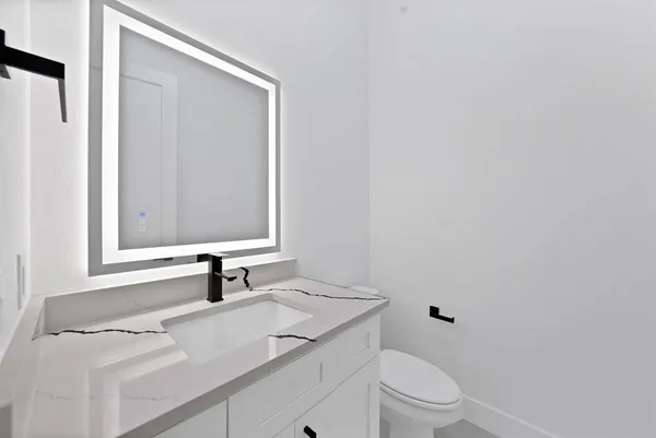 a bathroom with a sink toilet vanity and mirror