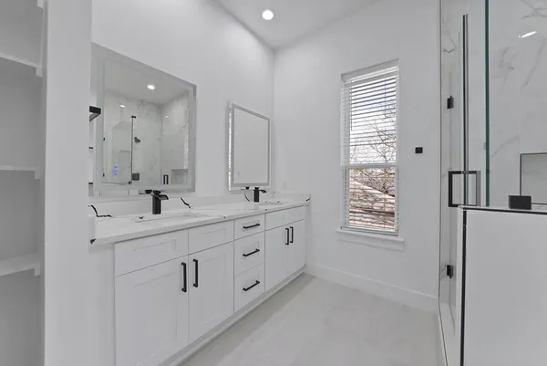 a bathroom with double vanity sink a window and a mirror