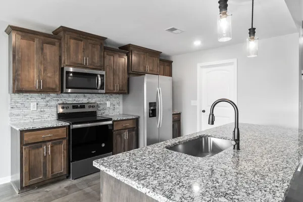 a kitchen with stainless steel appliances granite countertop a stove a sink dishwasher a refrigerator and a microwave