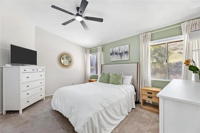 a bedroom with a large bed and a flat tv screen on dresser
