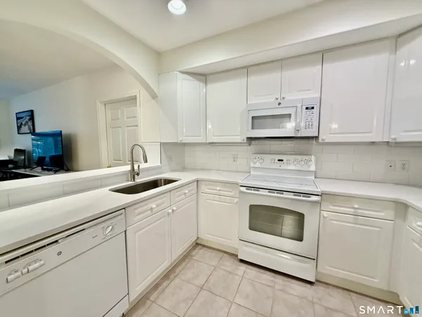 a kitchen with white cabinets and white appliances