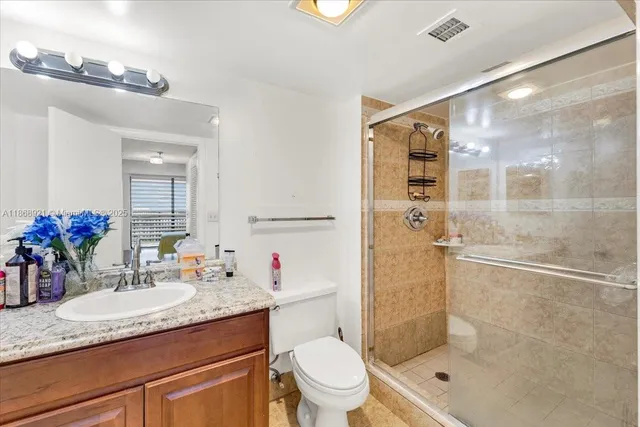 a bathroom with a granite countertop sink a toilet and shower