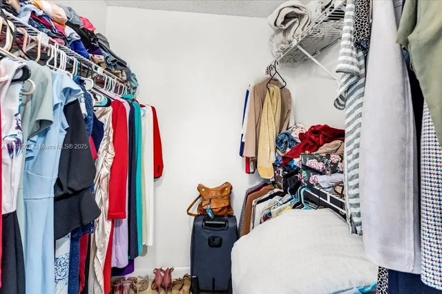a view of walk in closet with clothes and shoes