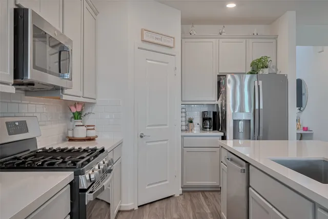a kitchen with white cabinets and stainless steel appliances