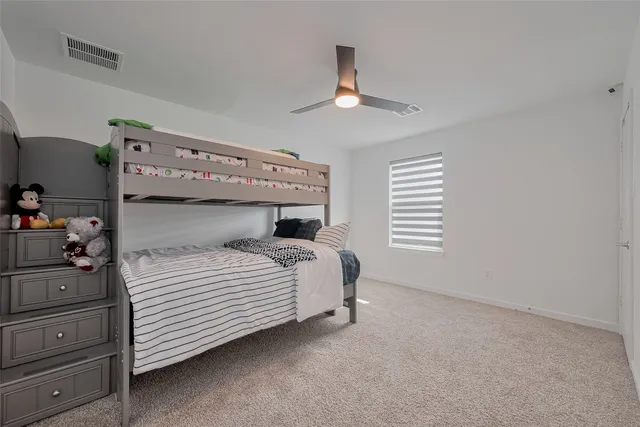 a bed sitting in a room next to a ceiling fan