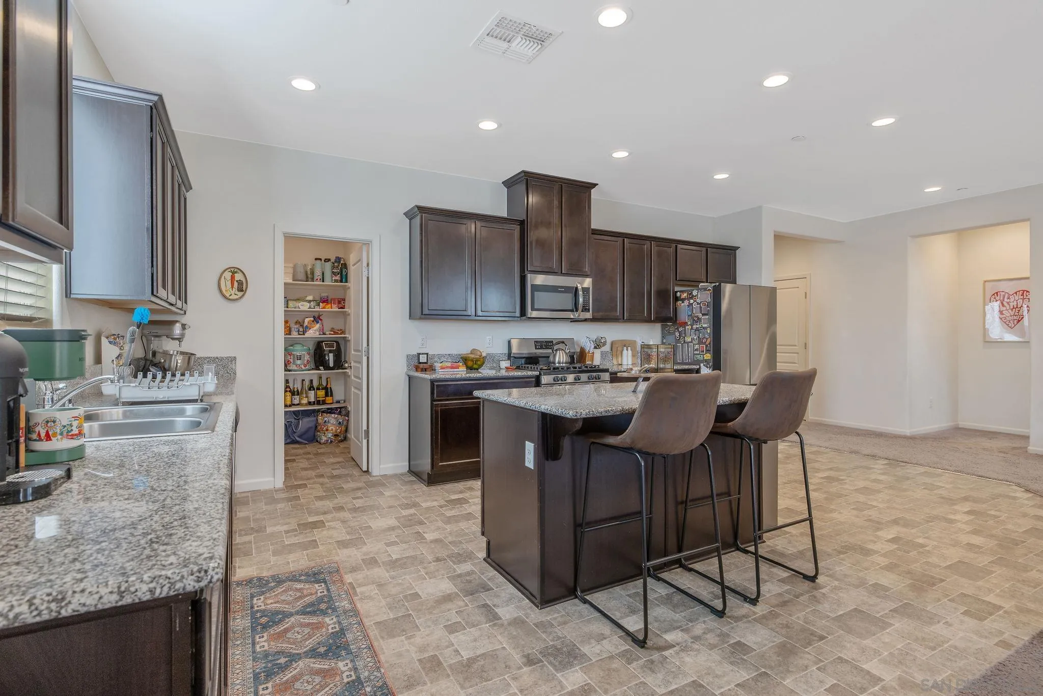 495 Pearl Drive Lemoore, CA 93245 - Photo 20 of 45 a kitchen with kitchen island granite countertop wooden cabinets and a refrigerator
