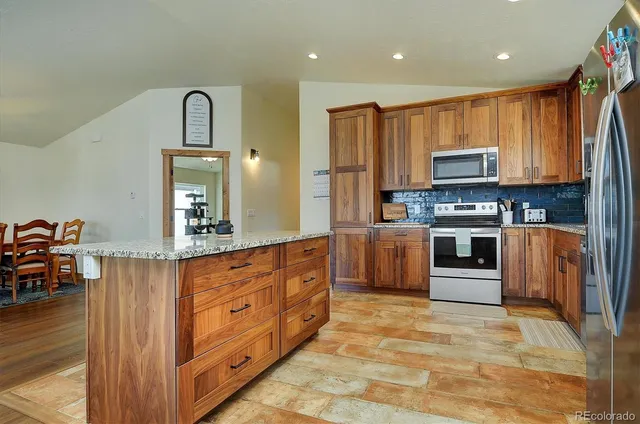 a kitchen with stainless steel appliances granite countertop a stove a sink and a refrigerator