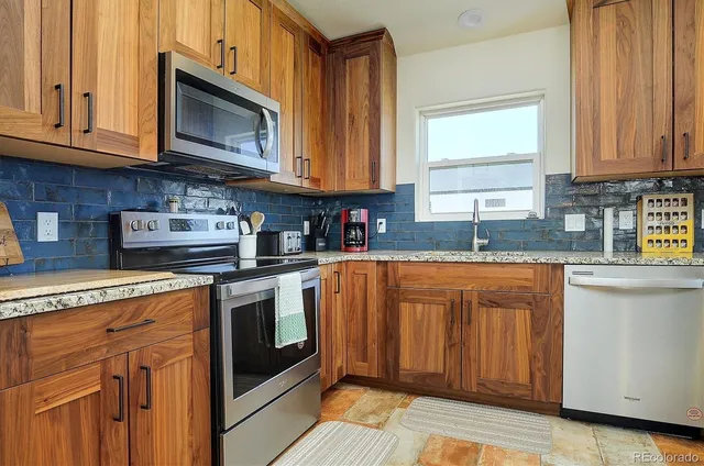 a kitchen with stainless steel appliances granite countertop a stove a sink and a microwave