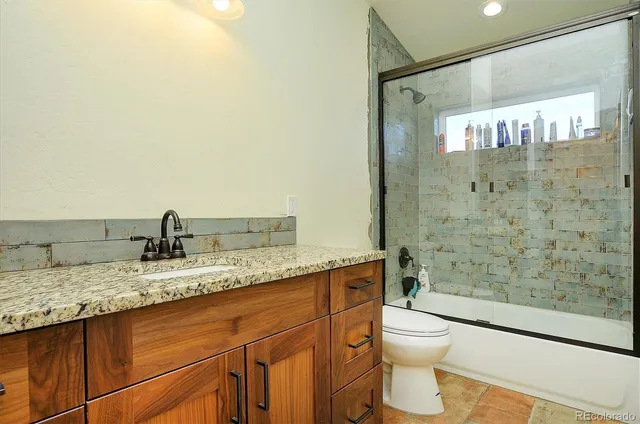 a bathroom with a granite countertop sink toilet and shower
